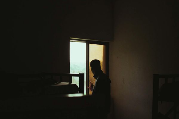 A person sitting calmly in a well-lit room, looking out a window.